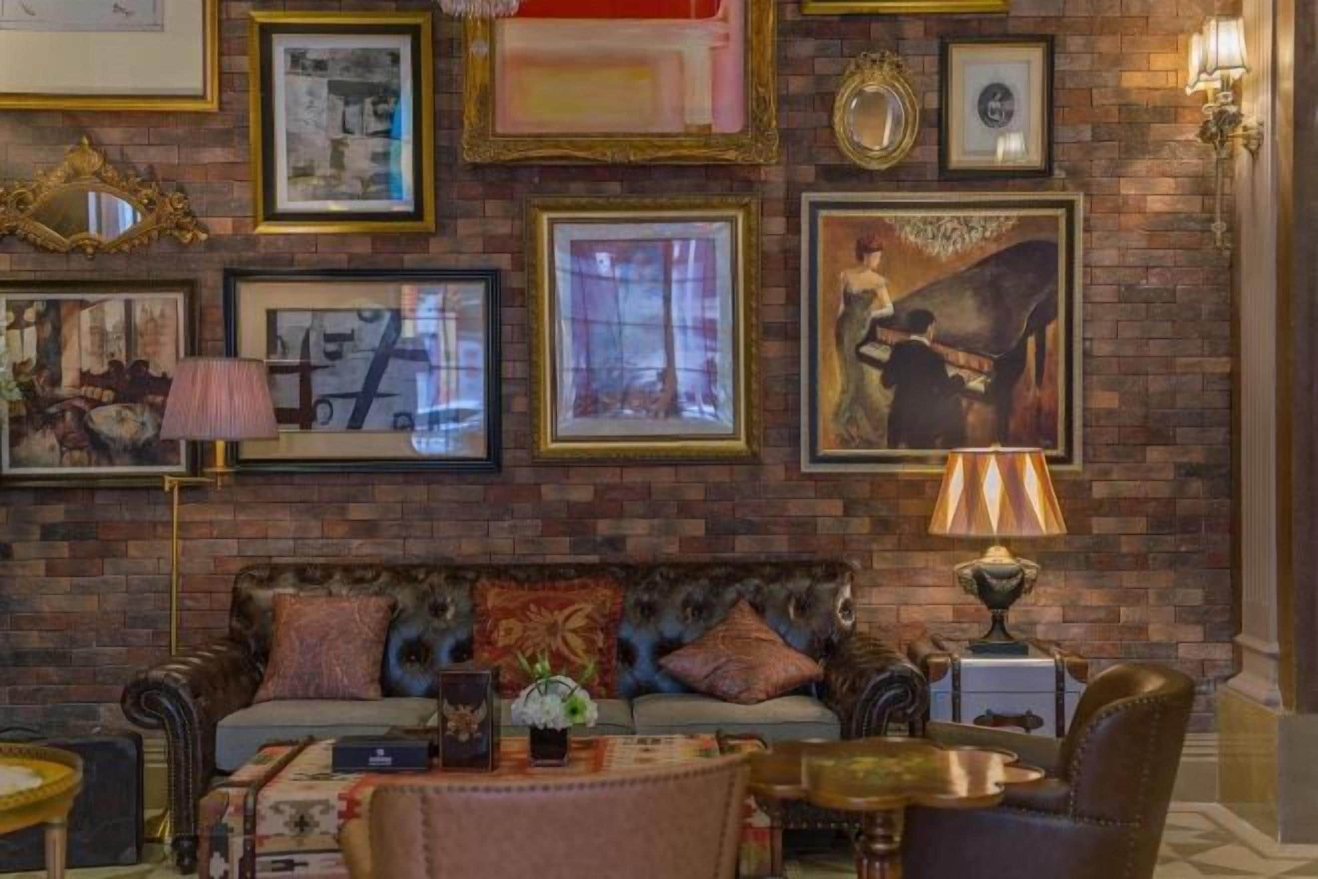 Une pièce avec un mur en briques, un canapé, une table et des tableaux encadrés.