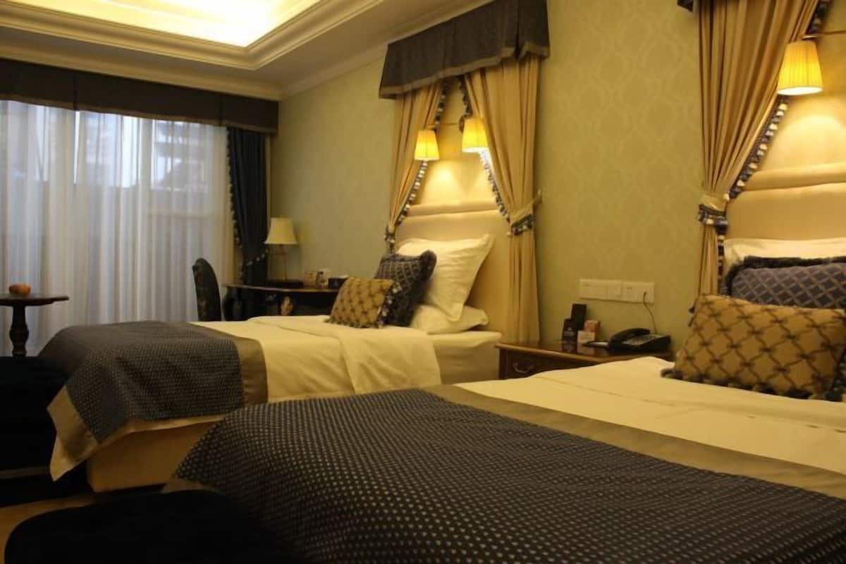 Habitación de hotel con dos camas, un escritorio, una silla y una lámpara.