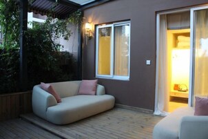 Una zona de estar al aire libre acogedora con un sofá acolchado y una terraza de madera.