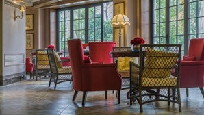 A room with red chairs, a table with a vase, and large windows. - Cannes City Hotel (Luzhou)