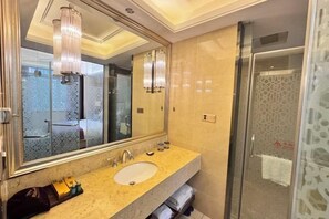 A modern bathroom with a large mirror, a sink, and a glass shower enclosure.