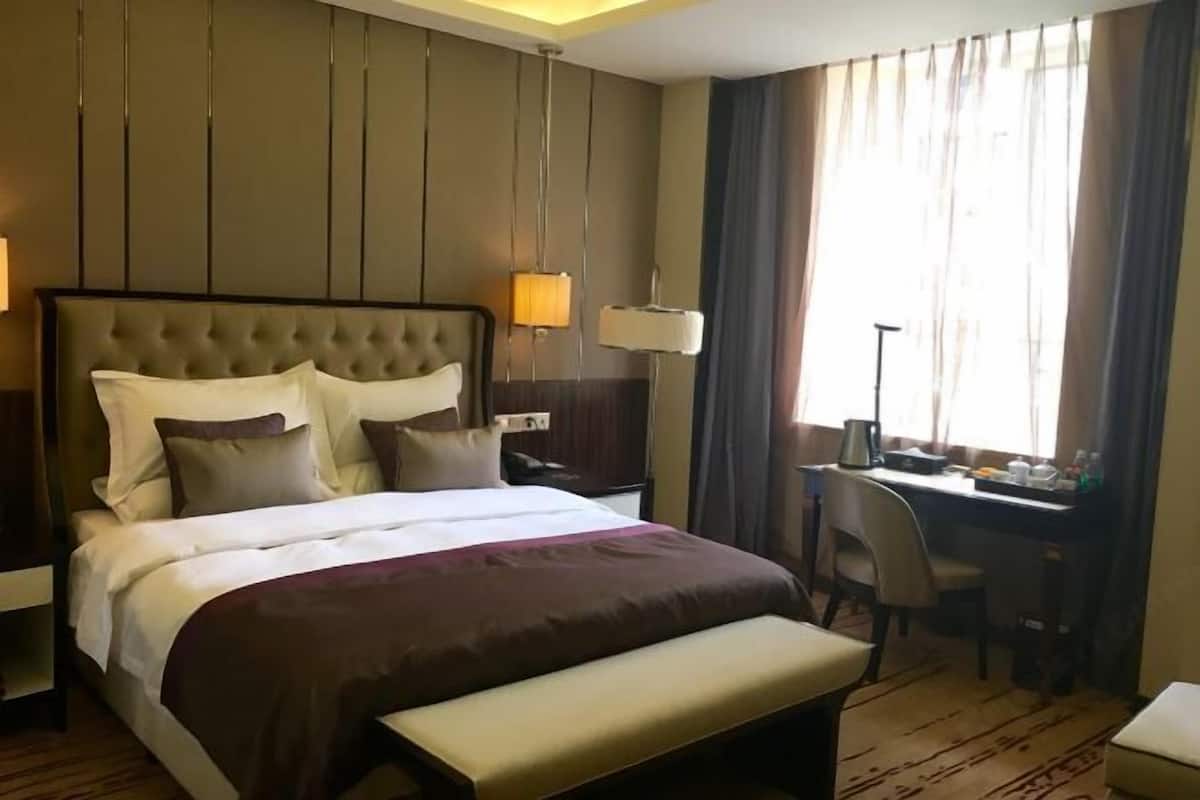 Habitación de hotel con una cama grande, mesitas de noche, un escritorio y una silla.