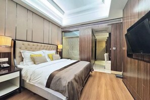 A modern hotel room with a large bed, a TV mounted on the wall, and a walk-in closet. - Cannes City Hotel (Luzhou)
