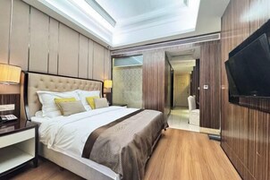 Una habitación de hotel moderna con una cama grande, un televisor en la pared y un vestidor.