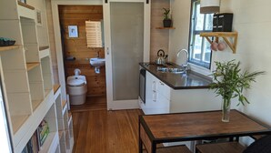 A compact kitchen with a sink, stove, and wooden cabinets. There is a small dining area with a table and chairs.