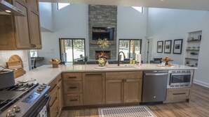 A modern kitchen with wooden cabinets, a built-in oven, a dishwasher, and a large island with a sink.