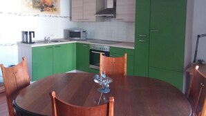 Una cocina con armarios verdes, una mesa de comedor de madera, un microondas y una estufa.