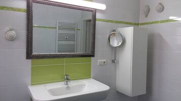 Un baño con un lavabo blanco, un espejo y azulejos verde a rayas.