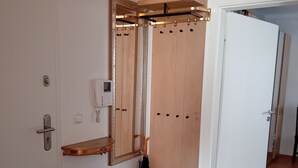 Un pasillo con una puerta de madera, un perchero, un espejo y un estante pequeño.