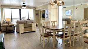 Un vaste espace de vie comprenant une table à manger, des chaises, un canapé et un lustre.