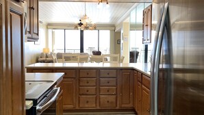 Une cuisine moderne avec des meubles en bois, un réfrigérateur en acier inoxydable et un grand îlot central doté d’un four encastré.