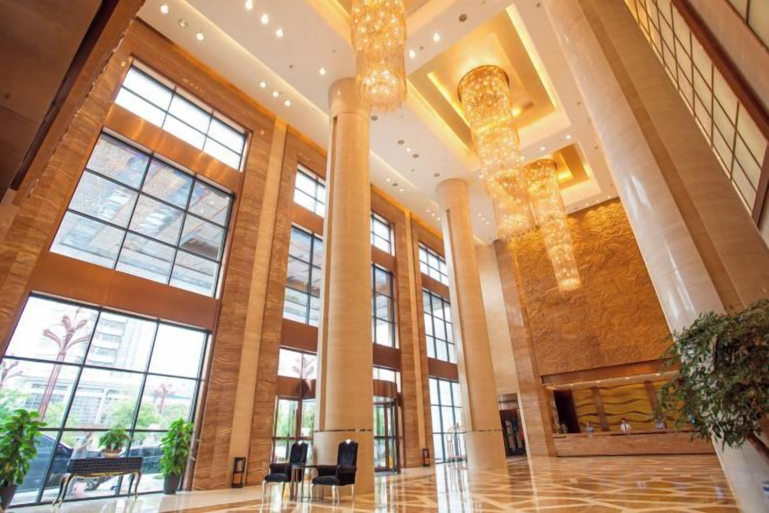 Un hall espacioso con techos altos, ventanas amplias y un candelabro.