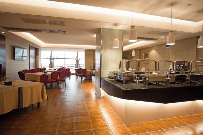 Un restaurante con mesas de comedor, una zona de cocina y un bufé.