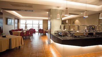 Un restaurante con mesas de comedor, una zona de cocina y un bufé.