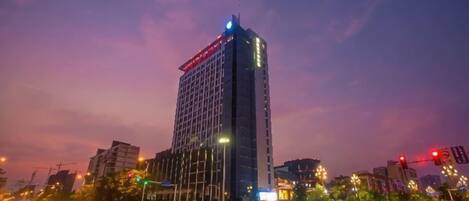 A high-rise building with a modern design, located in an urban setting with visible traffic and street lights.