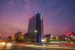 A high-rise building with a modern design, located in an urban setting with visible traffic and street lights. - Jinlong Yufeng Hotel (Changde Huanlecheng High Speed Railway Station) (Changde)