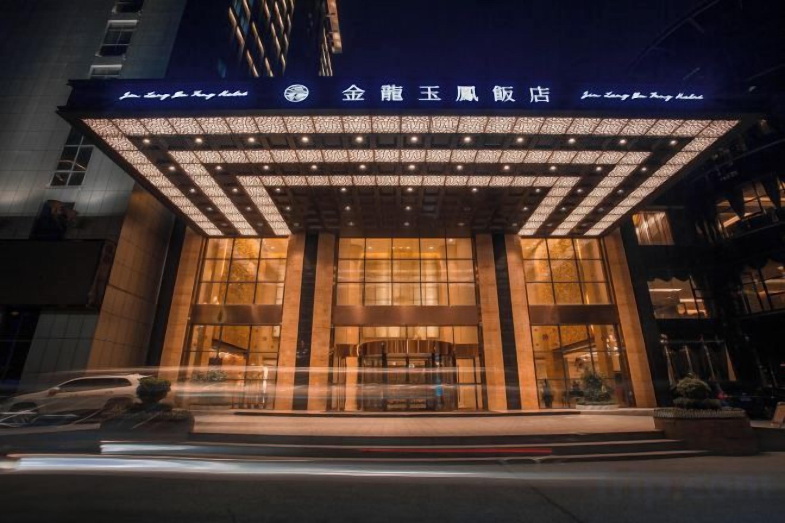 A hotel entrance with a covered entrance and illuminated signage.