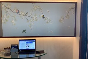 A laptop on a glass table with a painting of birds on a branch above. - Jinlong Yufeng Hotel (Changde Huanlecheng High Speed Railway Station) (Changde)
