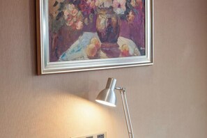 A framed painting of flowers on a wall, a desk lamp, and a power outlet. - Jinlong Yufeng Hotel (Changde Huanlecheng High Speed Railway Station) (Changde)