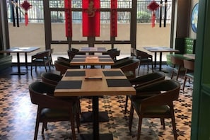 A restaurant with multiple tables and chairs, a patterned floor, and red decorations. - Heyue Hotel（Olympic Sports Center Store） (Jinan)