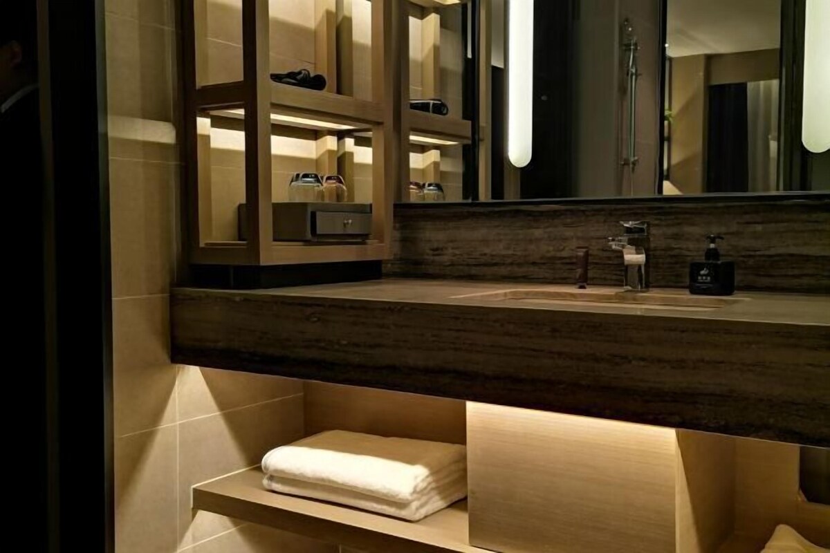 Une salle de bain moderne avec un meuble-lavabo en bois, un grand miroir et un porte-serviettes.