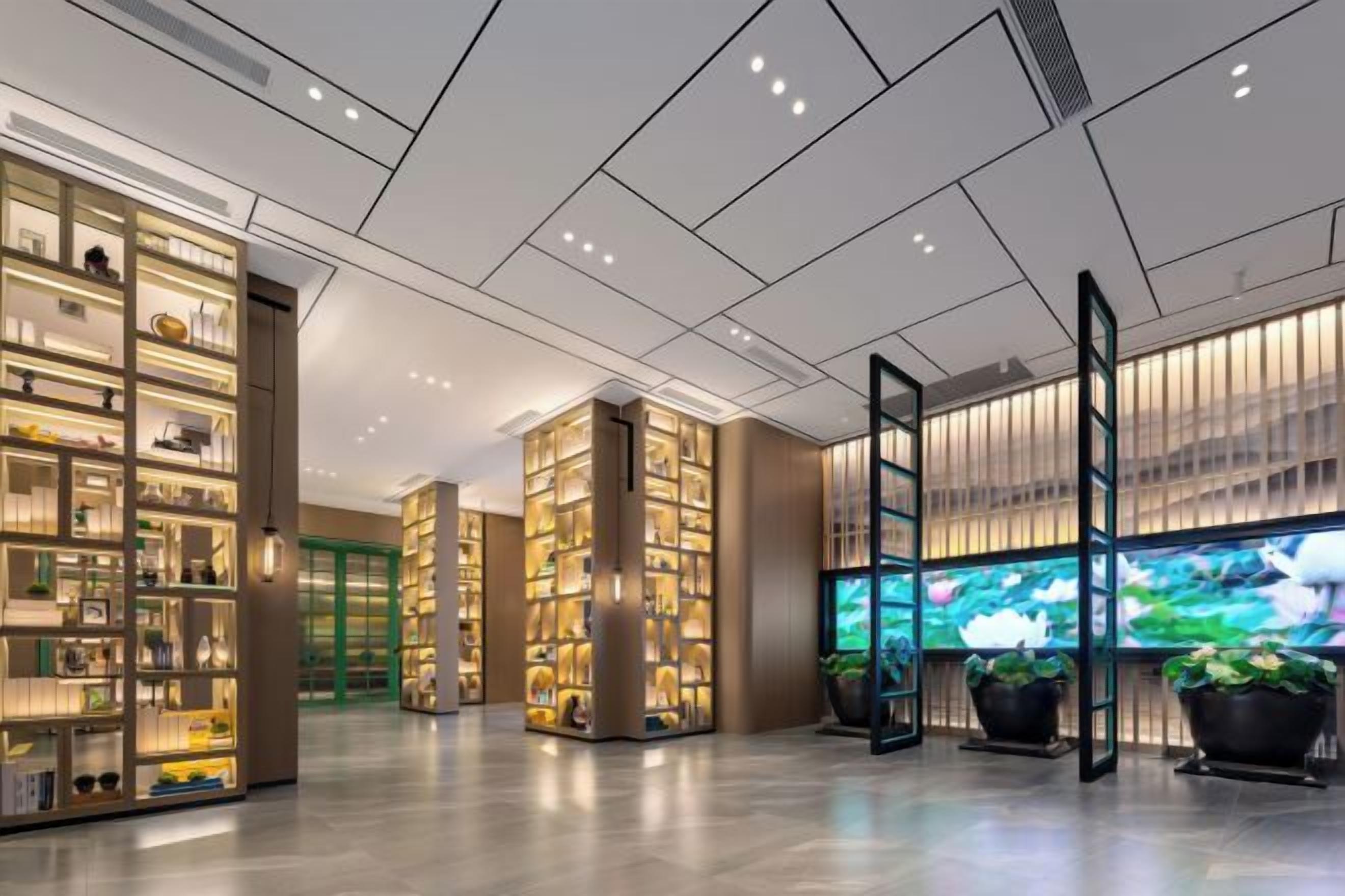 En rummelig lobby med flere reoler der udstiller diverse genstande, et stort digitalt display og plantekasser.