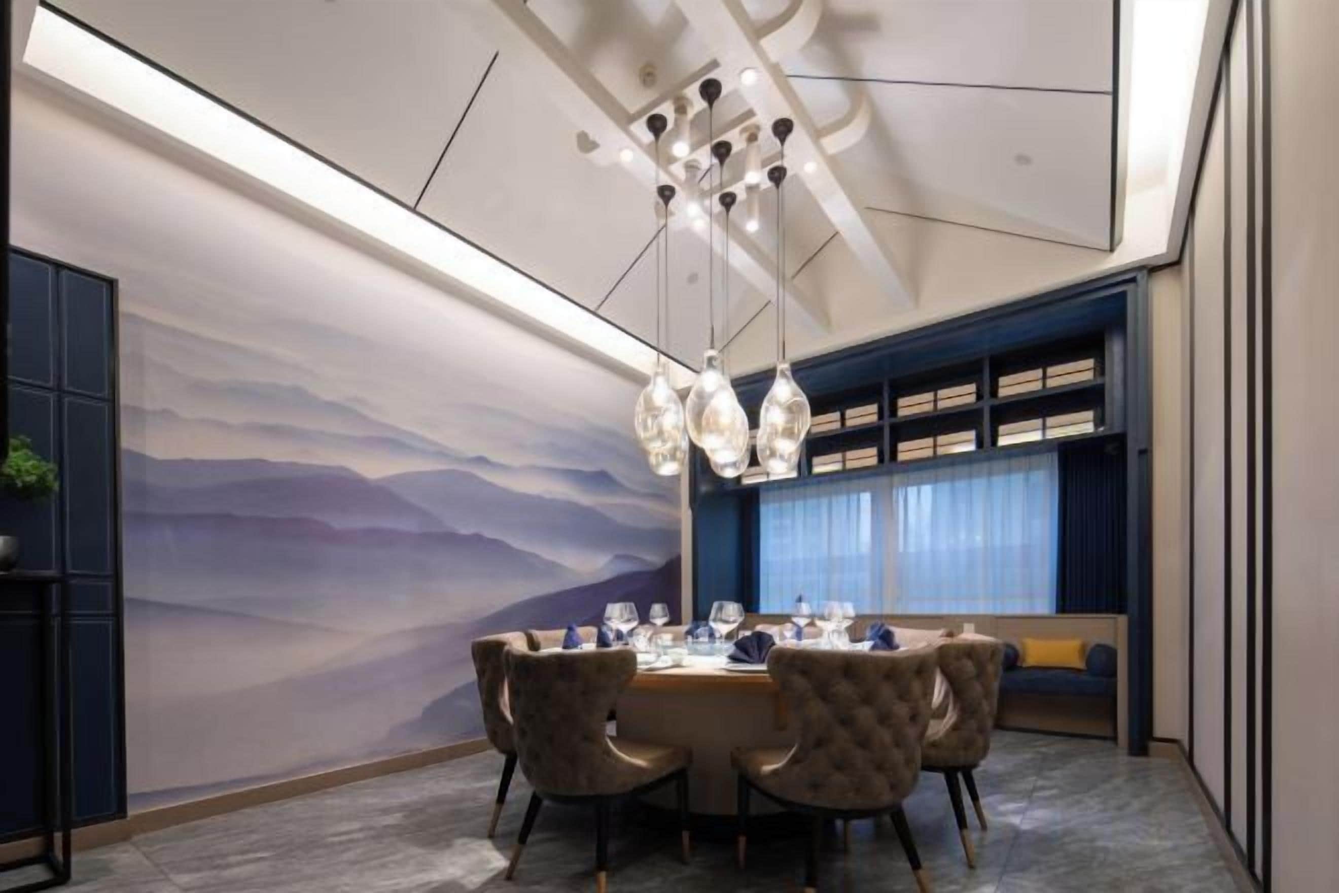 A dining area with a round table, chairs, and a wall mural.