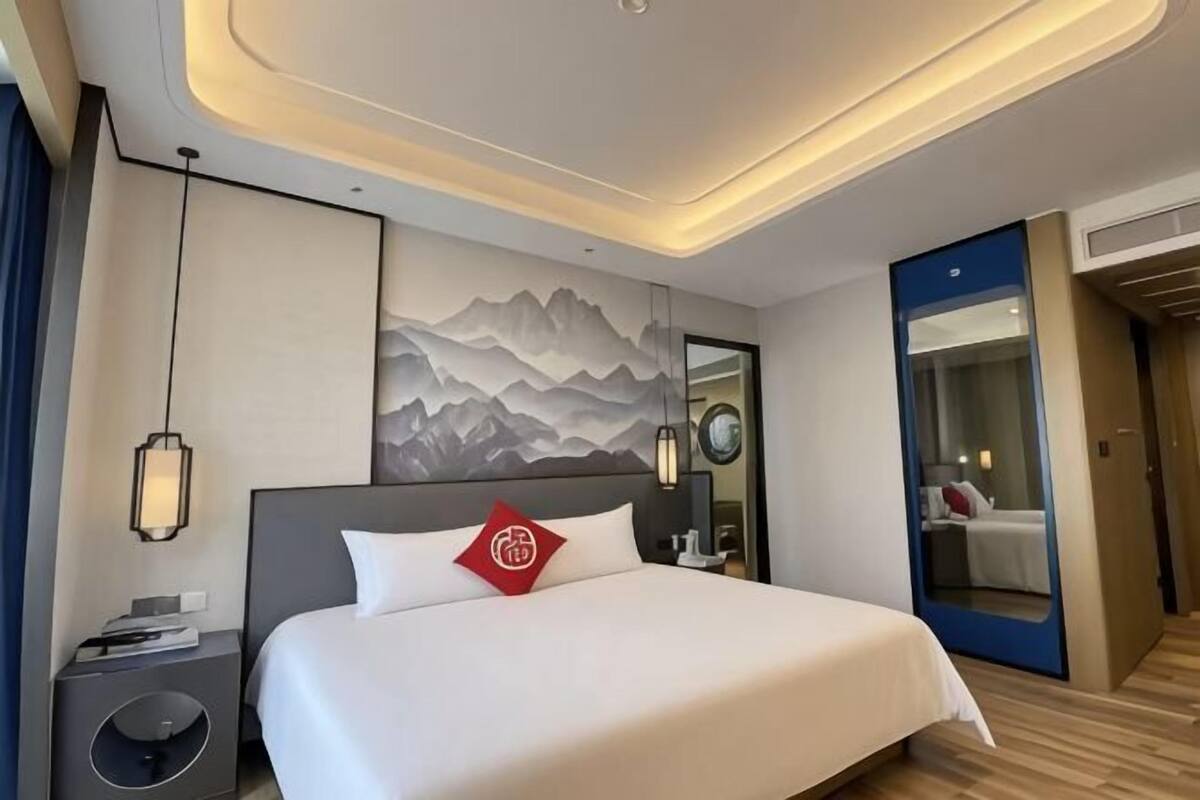 Habitación de hotel moderna con una cama grande, mesita de noche y una obra de arte colgada en la pared.