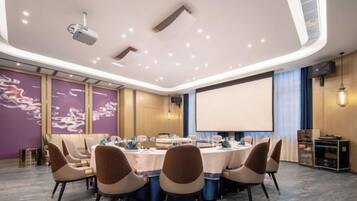 A conference room with a round table, chairs, a projector, and a screen.