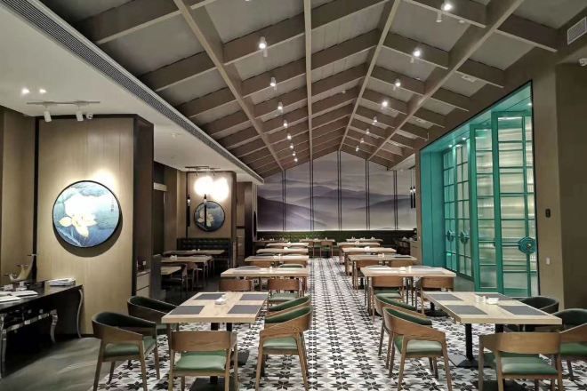 A restaurant with a high ceiling, round tables, and chairs.