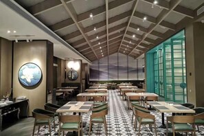 A restaurant with a high ceiling, round tables, and chairs. - Heyue Hotel（Olympic Sports Center Store） (Jinan)