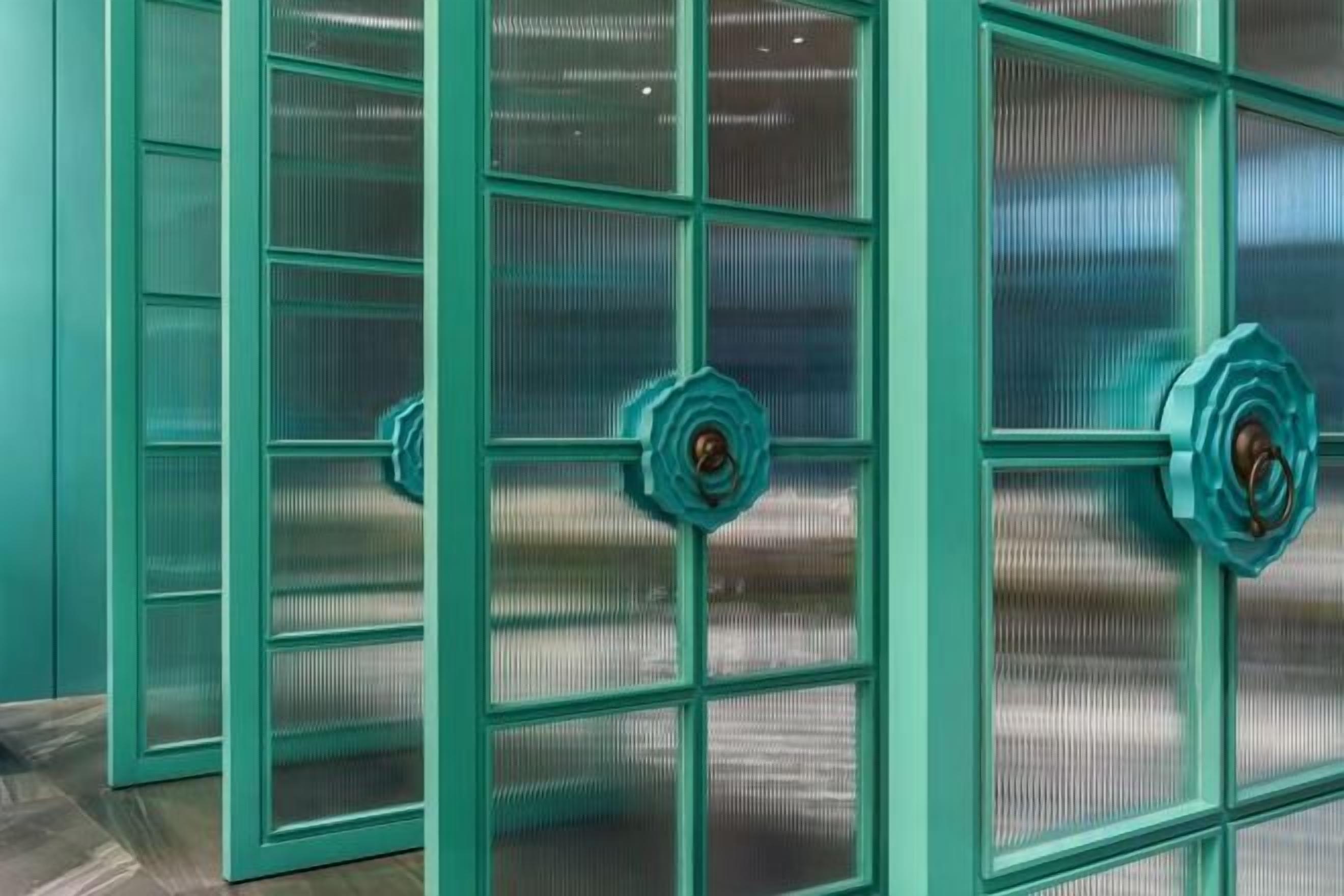 A set of teal-framed windows with a central locking mechanism.