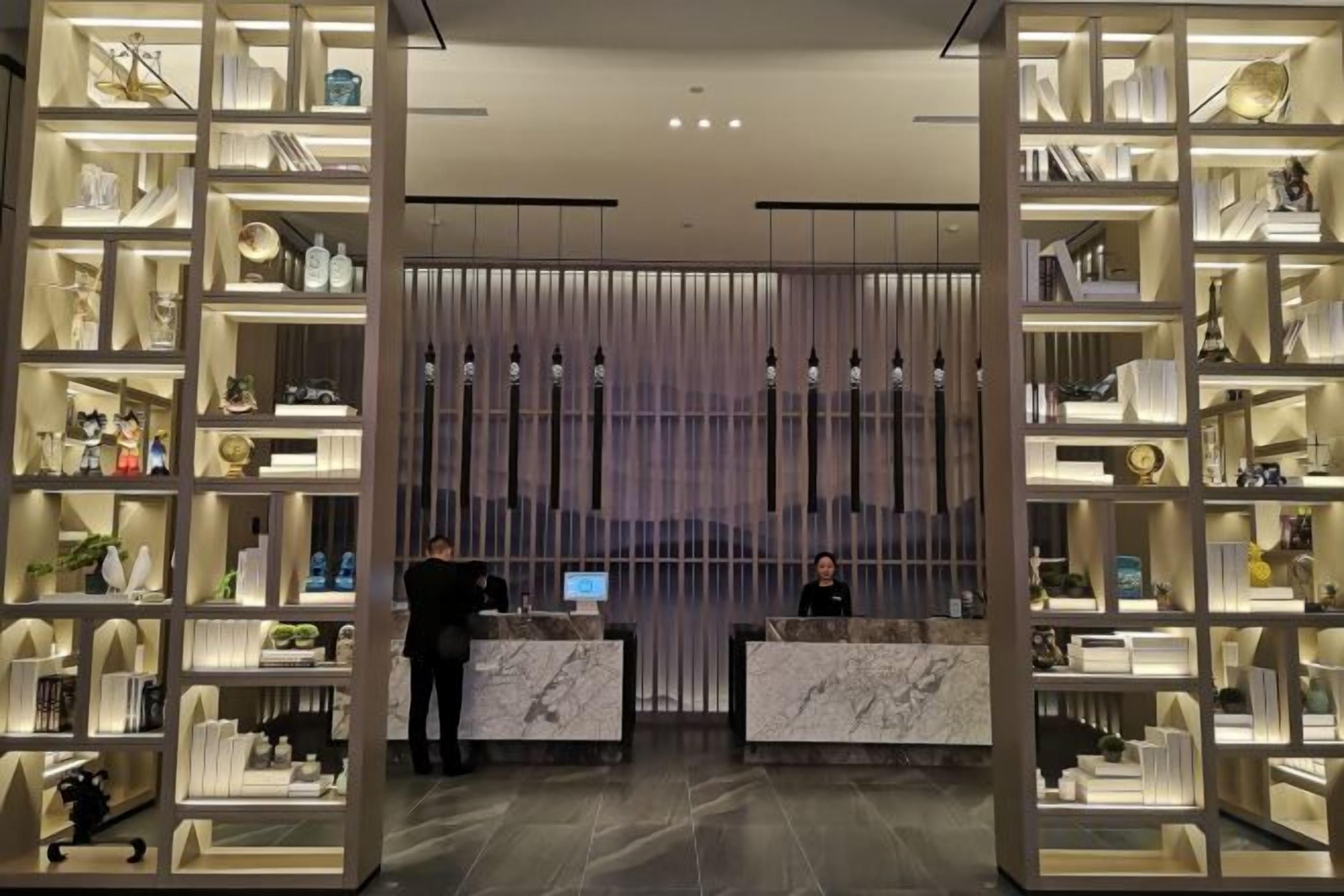 A reception area with marble counters, shelves with various items, and a modern design.