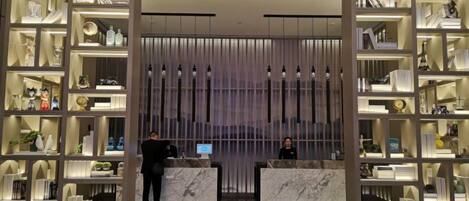 A reception area with marble counters, shelves with various items, and a modern design.