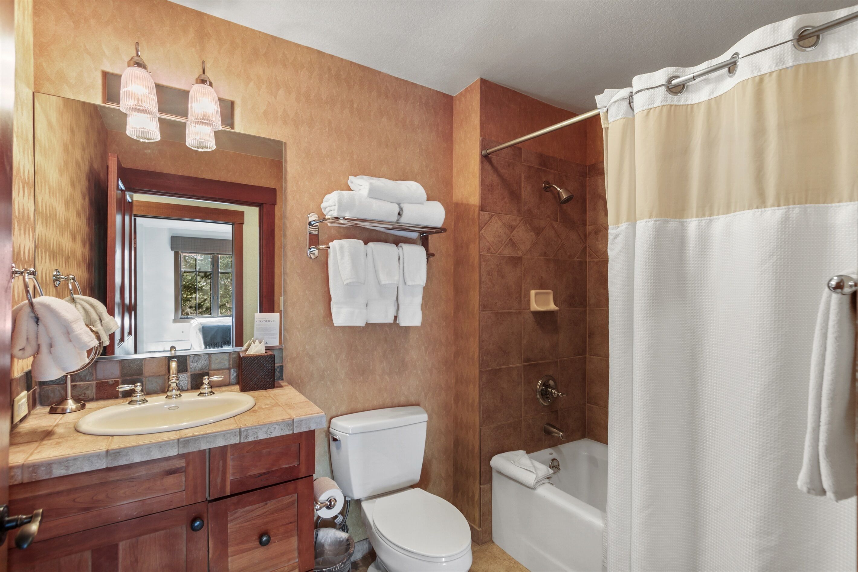 Une salle de bain avec un lavabo, des toilettes et une baignoire. Des serviettes sont suspendues sur un porte-serviettes et il y a un rideau de douche.