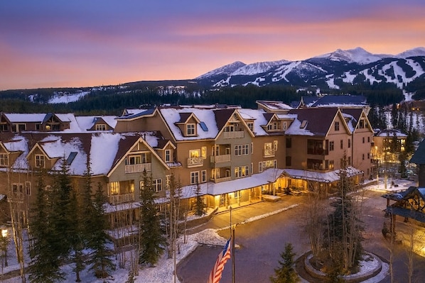 A hotel with multiple buildings, a snow-covered landscape, and a mountain in the background.