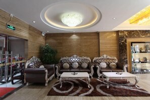 A lobby with a chandelier, sofas, and a coffee table.