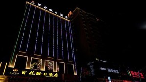 A multi-story building with illuminated signage and neon lights. - Baihua Holiday Hotel (Guangning)