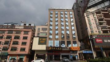 Un edificio de varios pisos con una entrada central, rodeado de otros edificios.