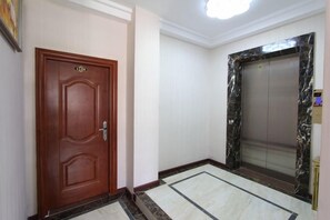 A hallway with a wooden door and an elevator.