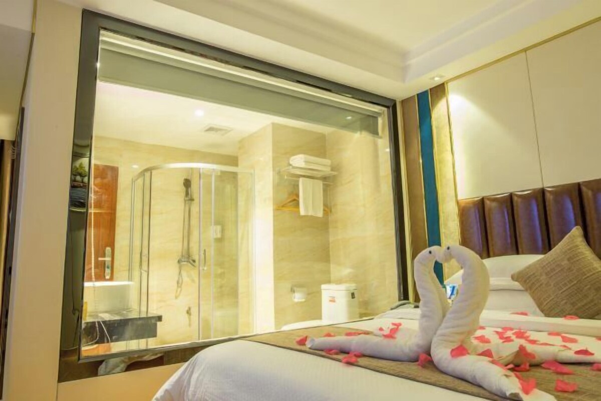 Een hotelkamer met een bed, een glazen douchecabine en uitzicht op de badkamer.