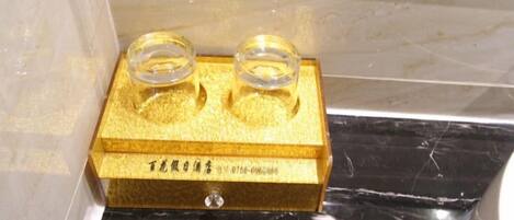 A gold-colored object with two clear glass containers on top, placed on a surface with a reflective black and white pattern.