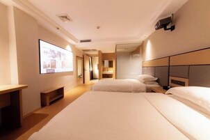 Ein Hotelzimmer mit einem großen Bett, einem Schreibtisch, einem Fernseher und einem Spiegel.