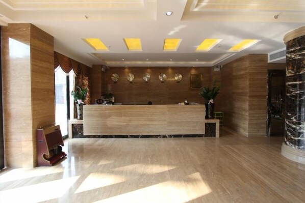 A hotel reception area with a marble reception desk, a large vase, and a wall-mounted clock. - Baihua Holiday Hotel (Guangning)