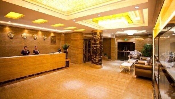 A hotel lobby with a reception desk, a large marble column, and a seating area with sofas and a coffee table. - Baihua Holiday Hotel (Guangning)