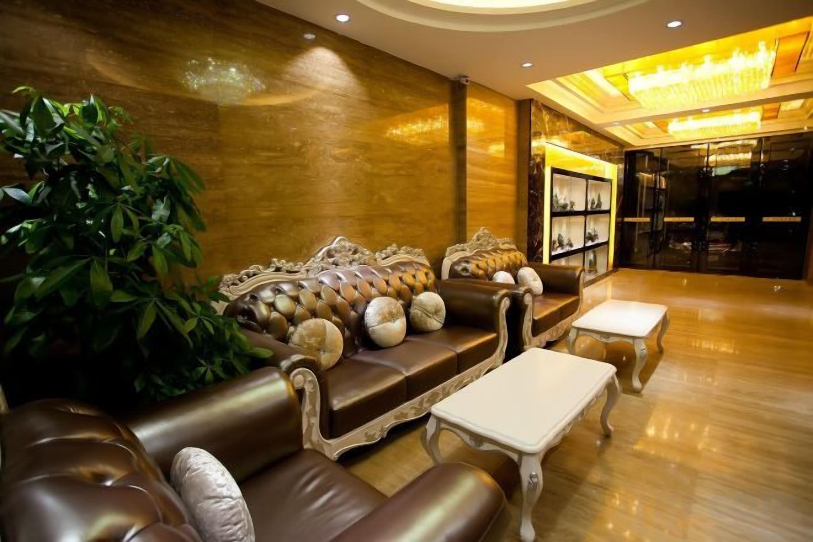 A luxurious lobby with a leather sofa, a white coffee table, and a large plant.