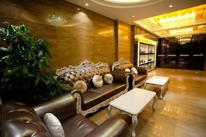 A luxurious lobby with a leather sofa, a white coffee table, and a large plant.