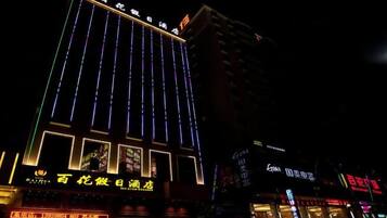 Un edificio de varios pisos con líneas verticales iluminadas y señalización.