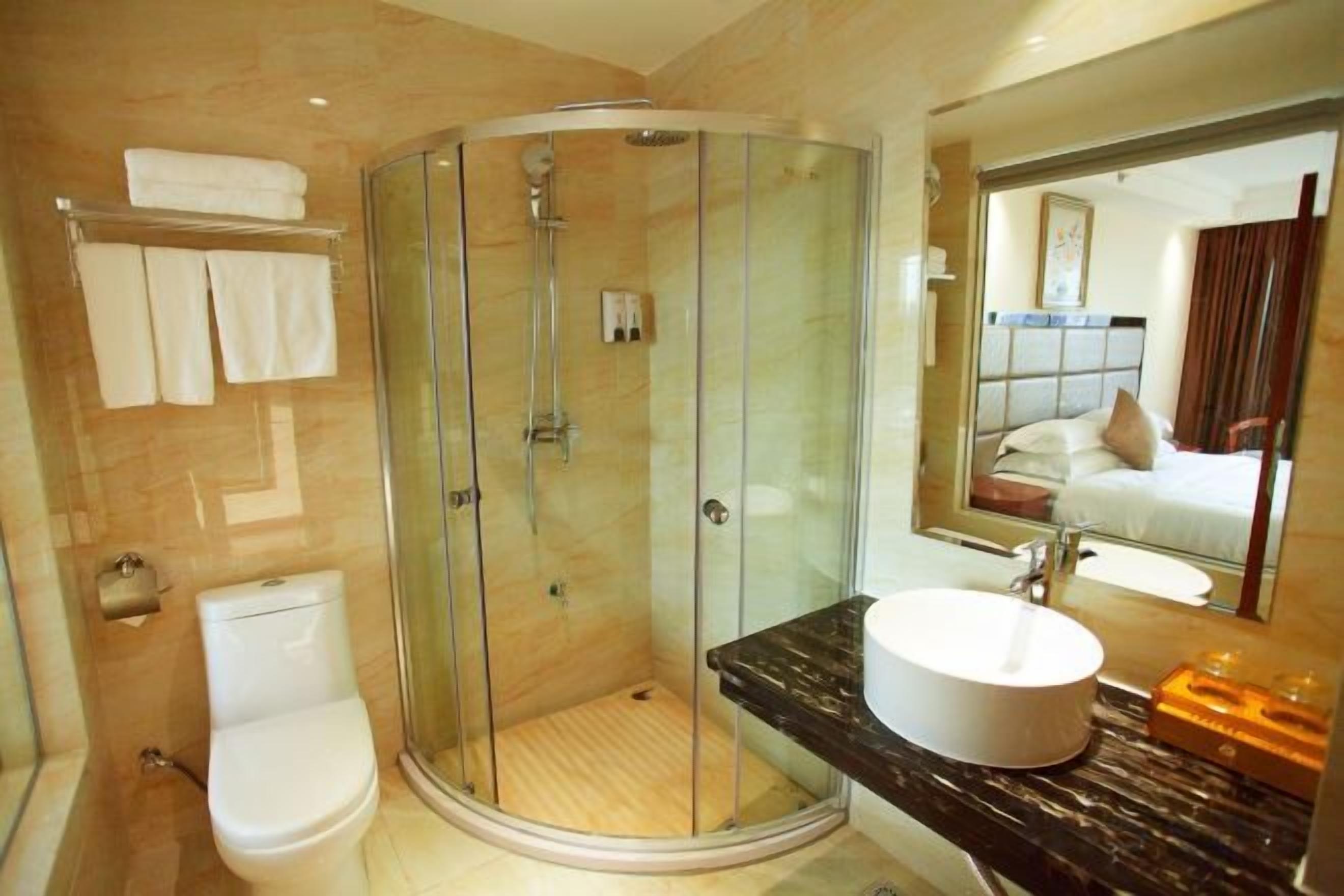 Un baño moderno con ducha envuelta en vidrio, inodoro e lavabo con encimera de mármol.