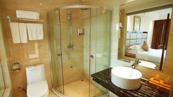 Un baño moderno con ducha envuelta en vidrio, inodoro e lavabo con encimera de mármol.